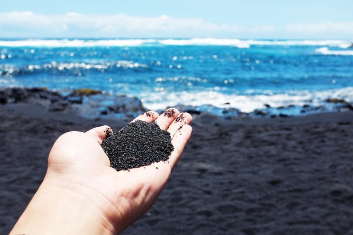 a hand holding a water bottle on a beach