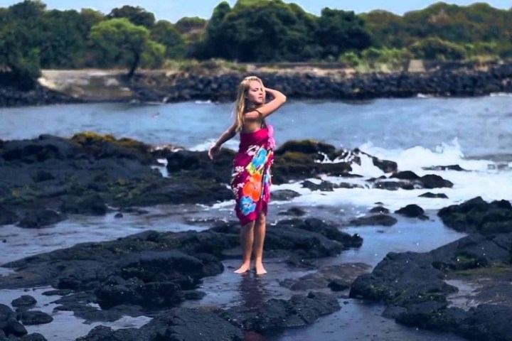 a little girl standing next to a body of water